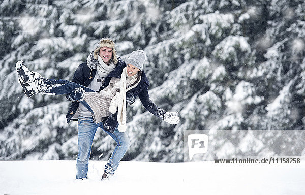 Man carrying girlfriend in winter landscape