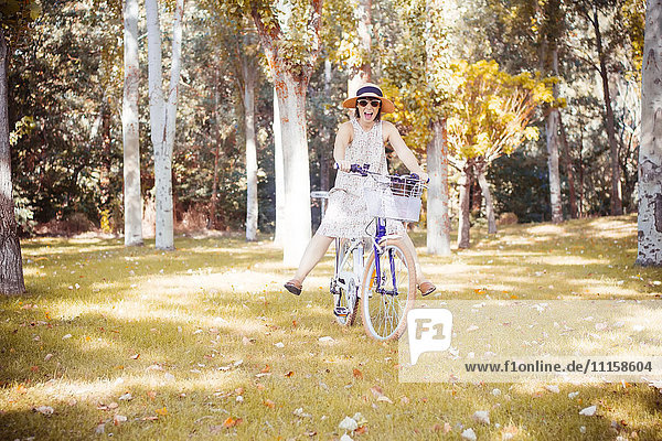 Frau balanciert auf dem Fahrrad im herbstlichen Park