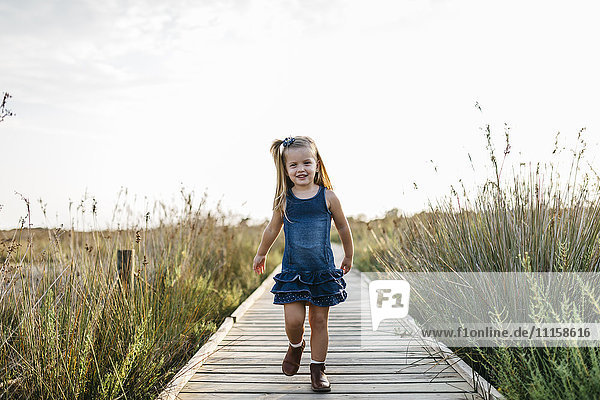 Smiling little girl walking on boardwalk in nature