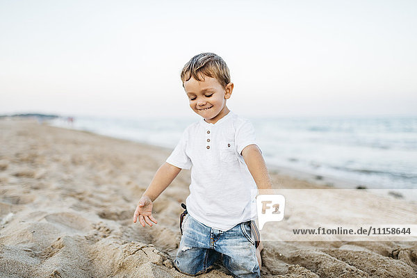 Glücklicher kleiner Junge  der am Strand spielt.