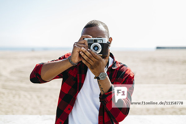 Man taking pictures with an old-fashioned camera near the beach