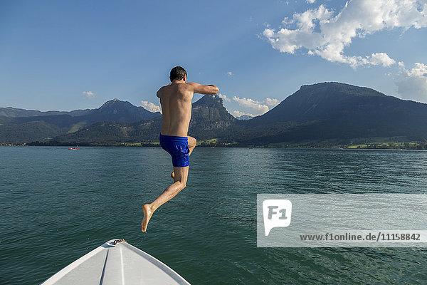 Österreich  Sankt Wolfgang  Mann springt vom Boot in den See