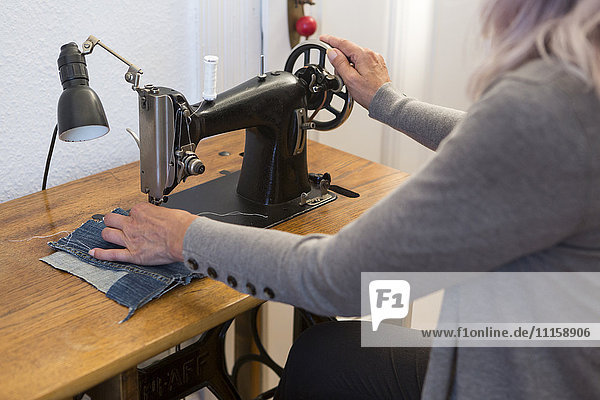 Woman working at sewing machine at home  partial view