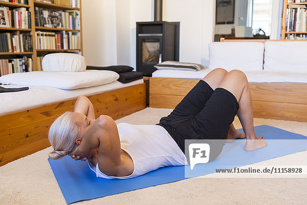 Woman exercising on gym mat in living room