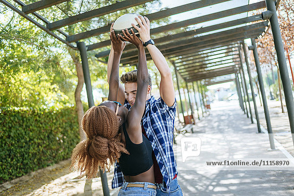 Happy young couple playing with a rugby ball