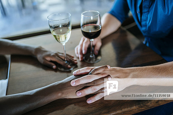 Nahaufnahme eines Händchen haltenden Paares im Restaurant