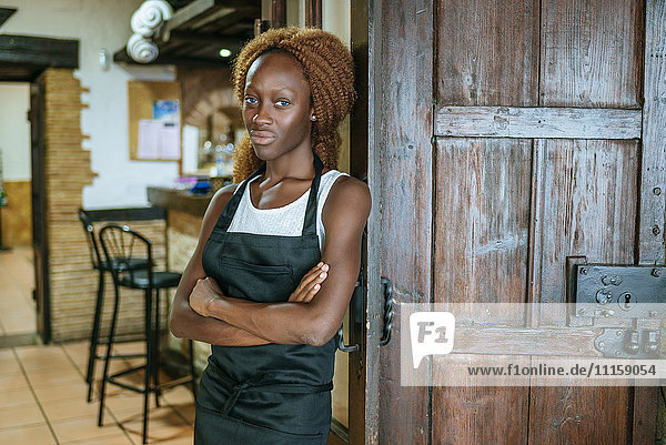 Portrait of young waitress at the door of a bar