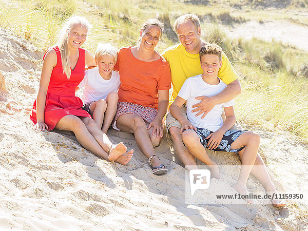 Glückliche Familie sitzt in den Dünen