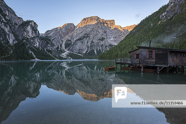 Italy  South Tyrol  Dolomites  Croda del Becco mountain and small wooden peir reflected in lake Braies at sunrise