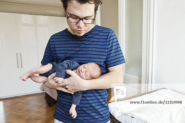 Father holding newborn son at home