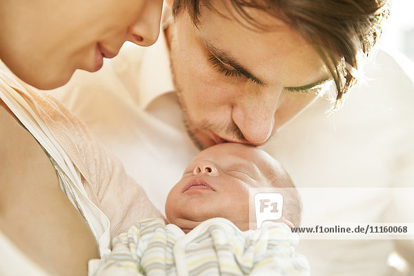 Nahaufnahme der Eltern beim Küssen und Halten des Neugeborenen