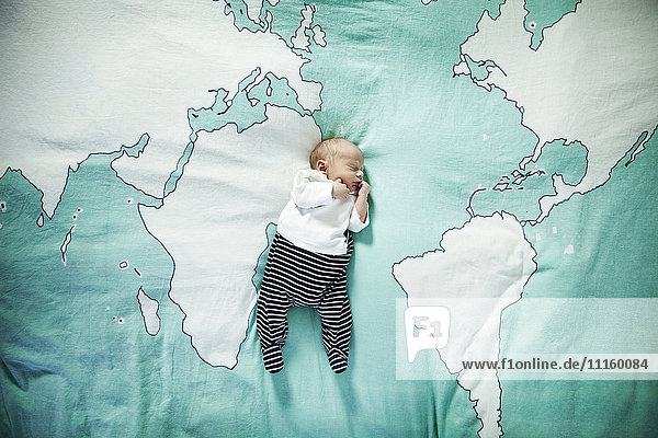 Newborn baby sleeping on blanket with world map
