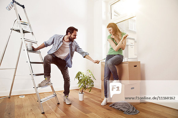 Verspieltes junges Paar beim Renovieren einer Wohnung