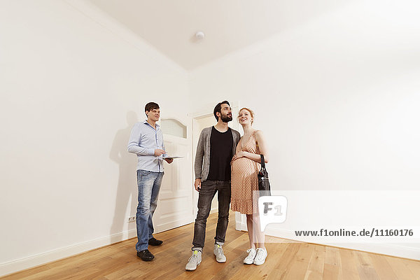 Real estate agent showing expecting parents around in a new apartment