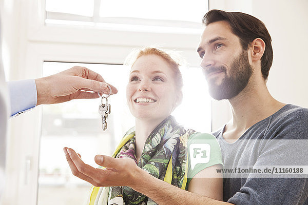 Young couple receiving house key from real estate agent