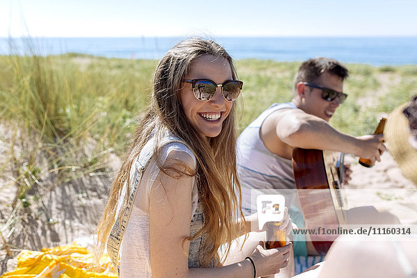 Porträt eines fröhlichen Teenagermädchens mit ihren Freunden am Strand