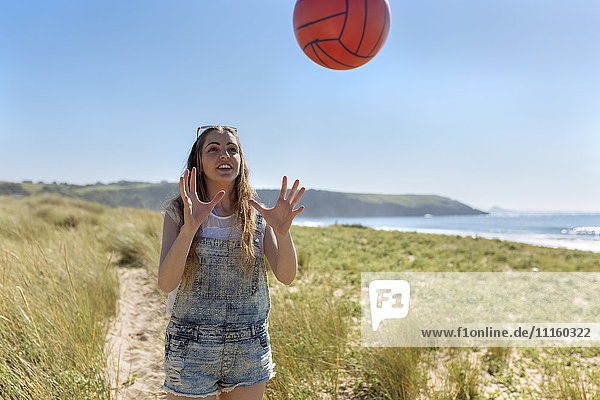 Smiling teenage girl playing on the beach with a ball