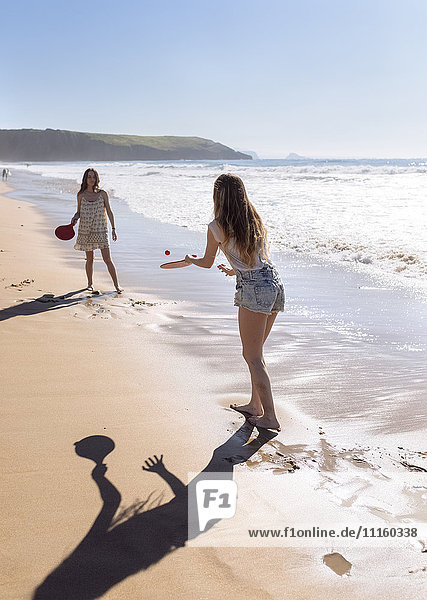 Two women playing beach paddles on the beach