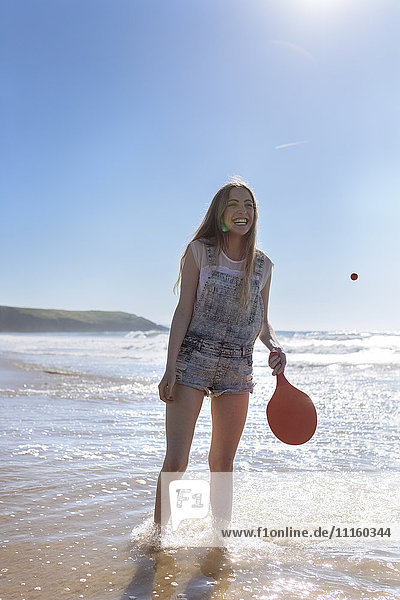 Happy teenage girl playing beach paddles on the beach