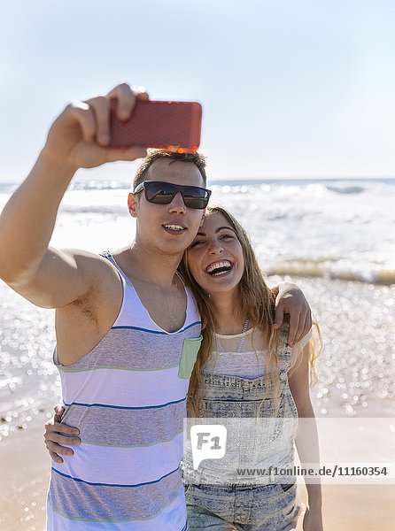 Young couple in love taking selfies on the beach