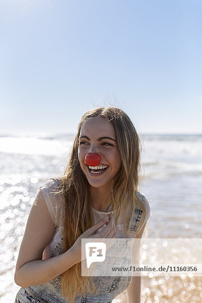 Portrait of smiling teenage girl with clown's nose at seaside