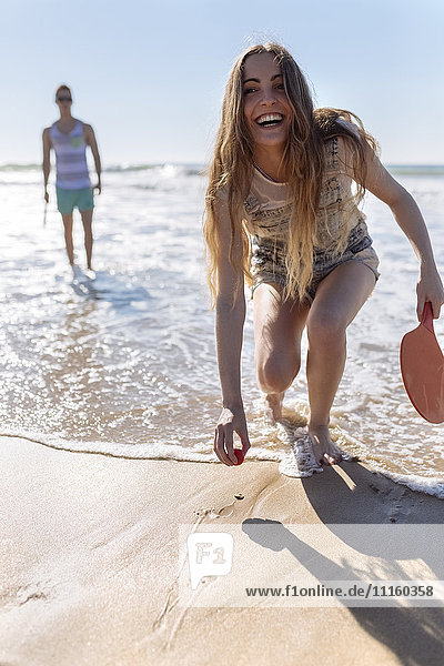 Laughing teenage girl playing beach paddles on the beach