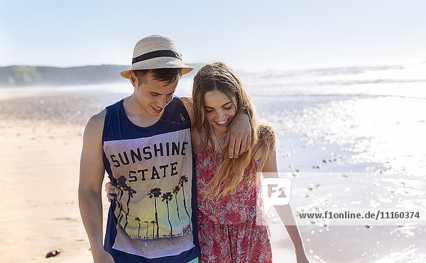 Ein glückliches junges verliebtes Paar  das am Strand spazieren geht.