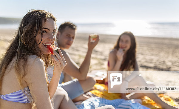 Friends eating watermelon on the beach