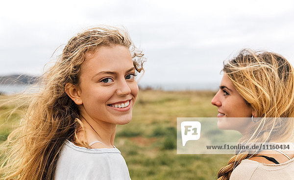 Smiling blond teenage girl and her best friend at the coast
