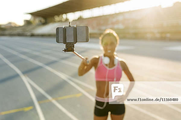 Sportlerin  die sich im Stadion selbstständig macht  mit einem Selfie-Stick.