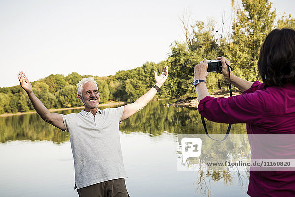 Happy senior couple at a lake taking pictures