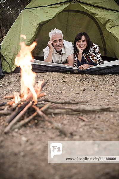 Glückliches Seniorenpaar liegt im Zelt am Lagerfeuer