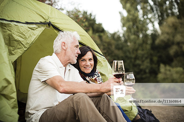 Seniorenpaar sitzend mit Wein im Zelt