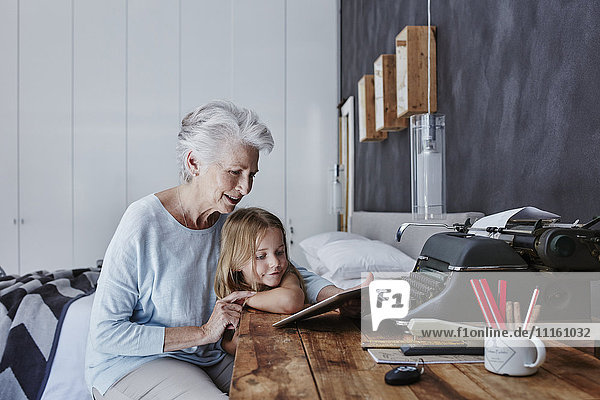 Großmutter und Enkelin beim Betrachten der Tablette zu Hause