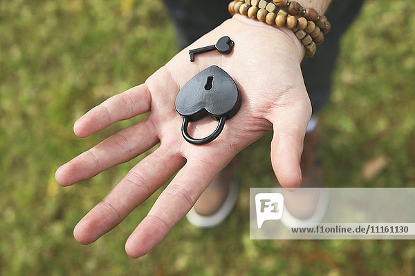 Heart-shaped love lock and key on man's palm  close-up