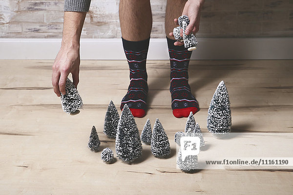 Young man wearing winter socks placing Christmas tree decoration on the floor