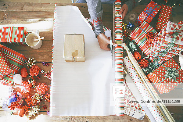 Frau schneidet Geschenkpapier für Weihnachtsgeschenke