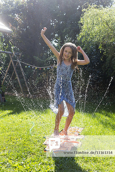 Girl having fun with inflatable water cushion in the garden