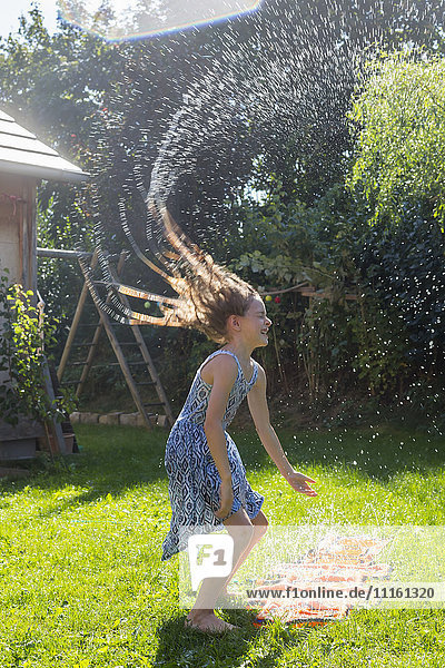 Girl having fun with inflatable water cushion in the garden