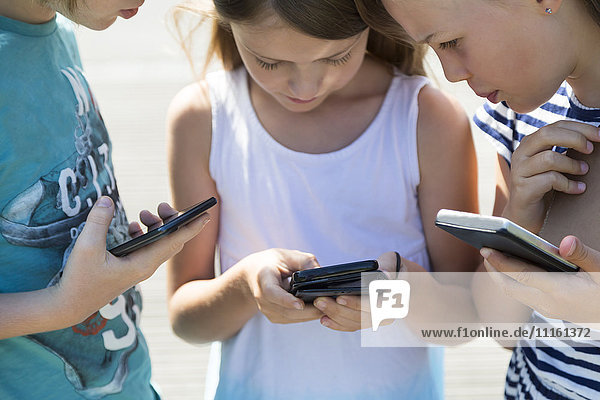 Three children with smartphones