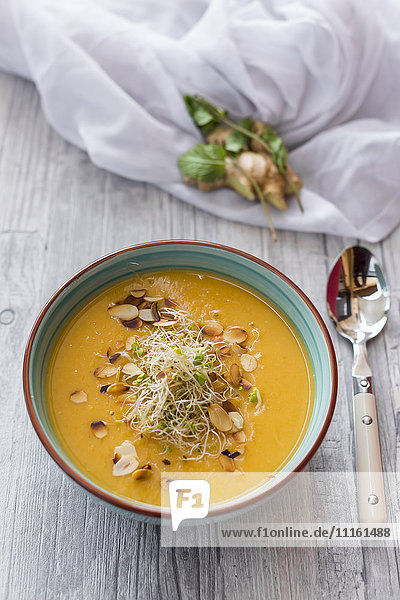 Bowl of sweet potato coconut soup with ginger  parsnip  leek  sprout and almond