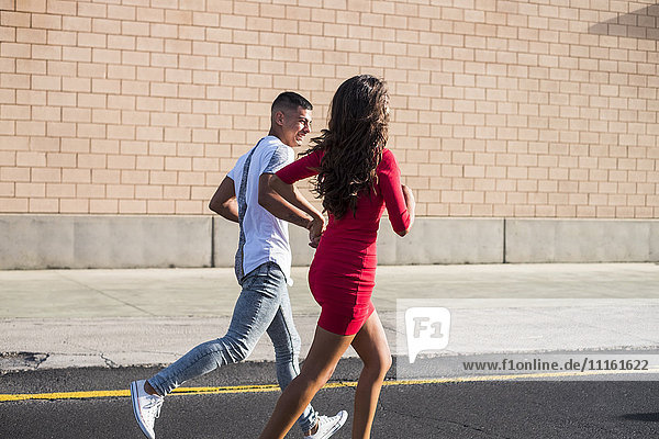 Teenage couple running hand in hand on a street