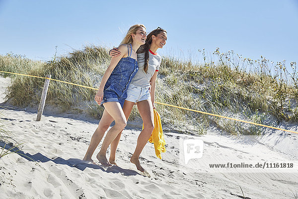Two happy female friends walking on the beach