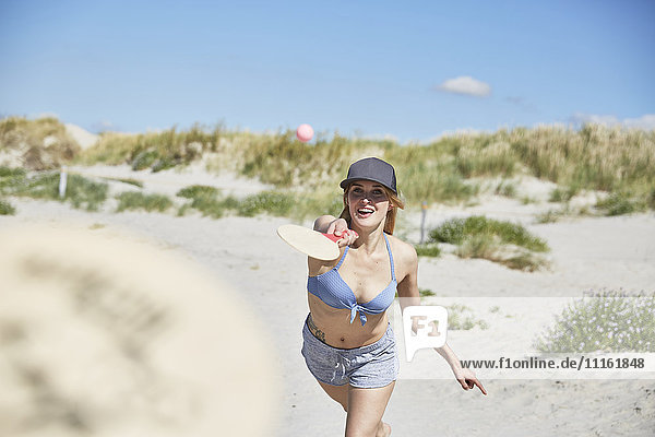 Fröhliche junge Frau am Strand beim Strandpaddeln