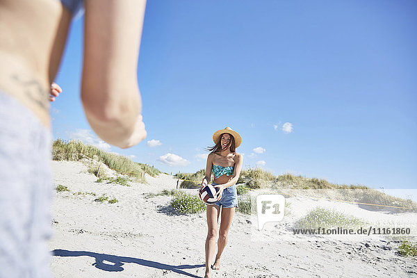 Junge Frau am Strand spielt Beachvolleyball