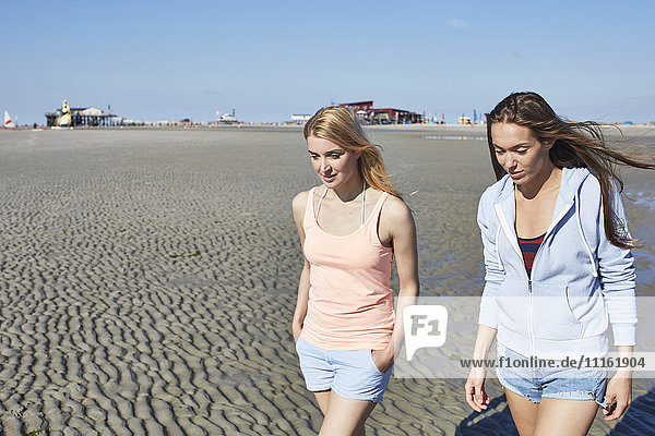 Zwei Freundinnen  die am Strand spazieren gehen.