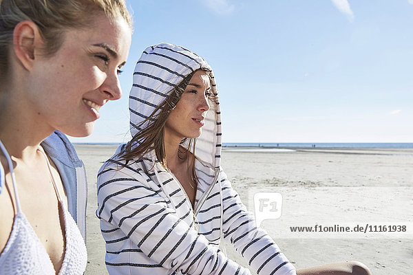Zwei Freundinnen mit Kapuzenpullover am Strand