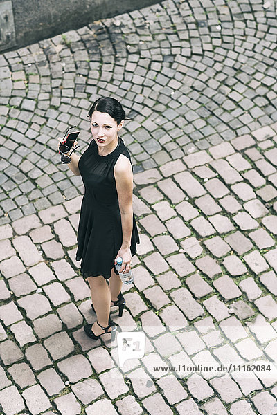 Junge Frau auf Kopfsteinpflaster stehend in schwarzem Kleid