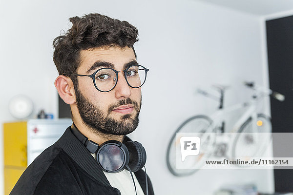Porträt eines Mannes mit Brille und Kopfhörer in einem modernen Büro