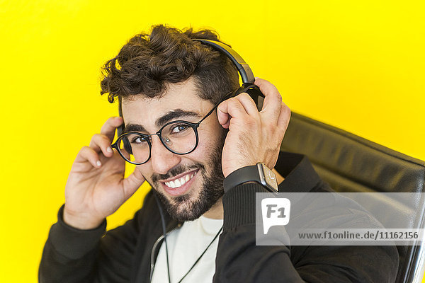 Portrait of smiling man with glasses putting on headphones